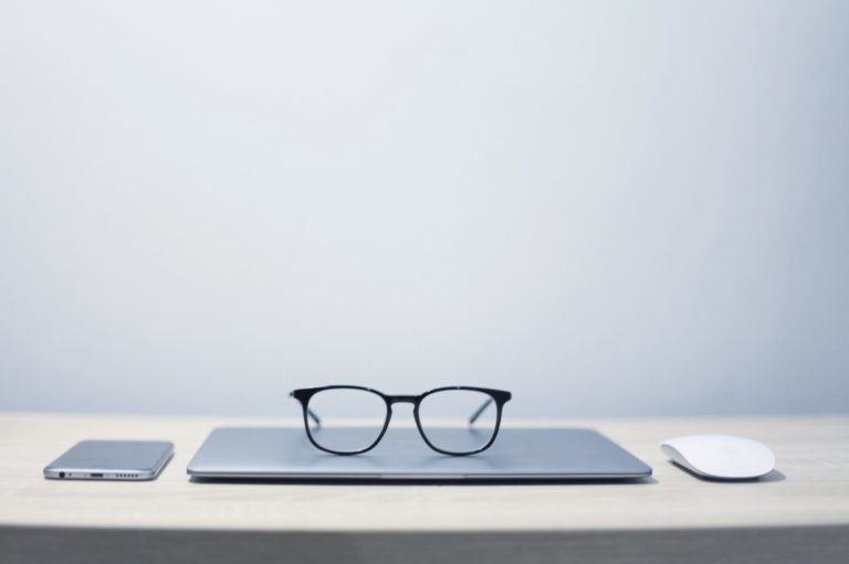 laptop on table closed with eye glasses on it