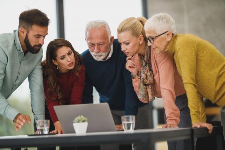 Multiracial group of professionals reviewing keyword data together on a laptop in a bright, modern office, symbolizing long-tail keyword research for B2B SEO