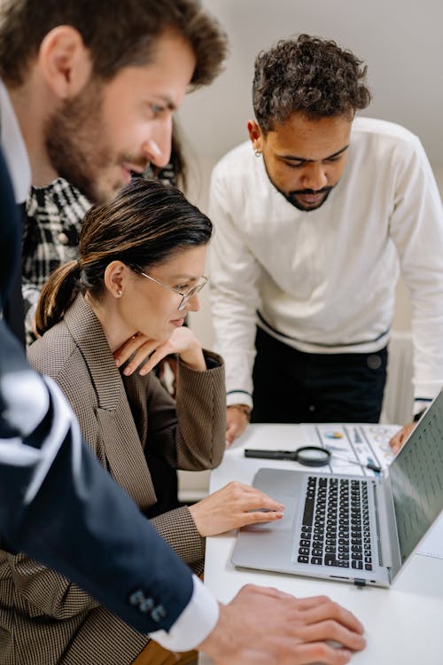 Diverse professionals working together at a laptop in a modern office, reviewing analytics to reduce bounce rate and drive sales.